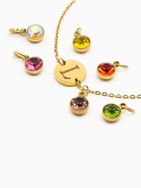 Foto de una medalla con la letra L y cuatro piedras circonitas de colores de la marca de joyas, AmaloA.