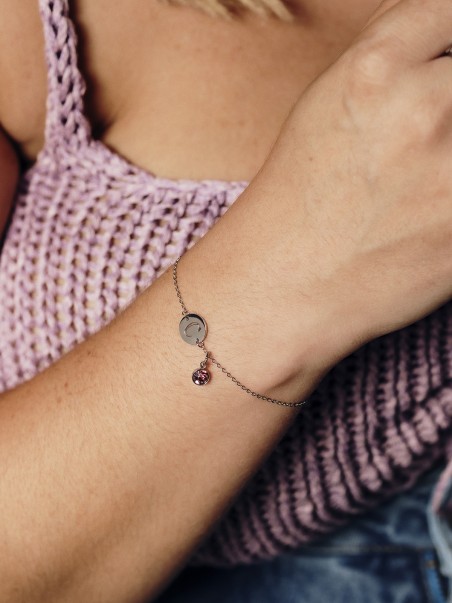 Foto de una mano luciendo una pulsera con la letra C y una circonita de color violeta de la marca de joyas AmaloA.