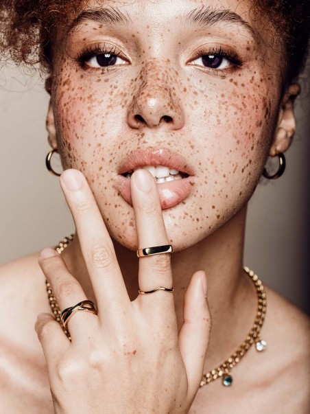Mujer posando con pendientes y anillos de la marca de joyas AmaloA.